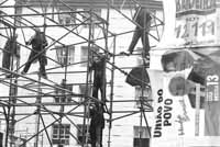Varias personas se suben a una estructura tubular para colgar los carteles de la Uni&oacute;n del Pueblo.
