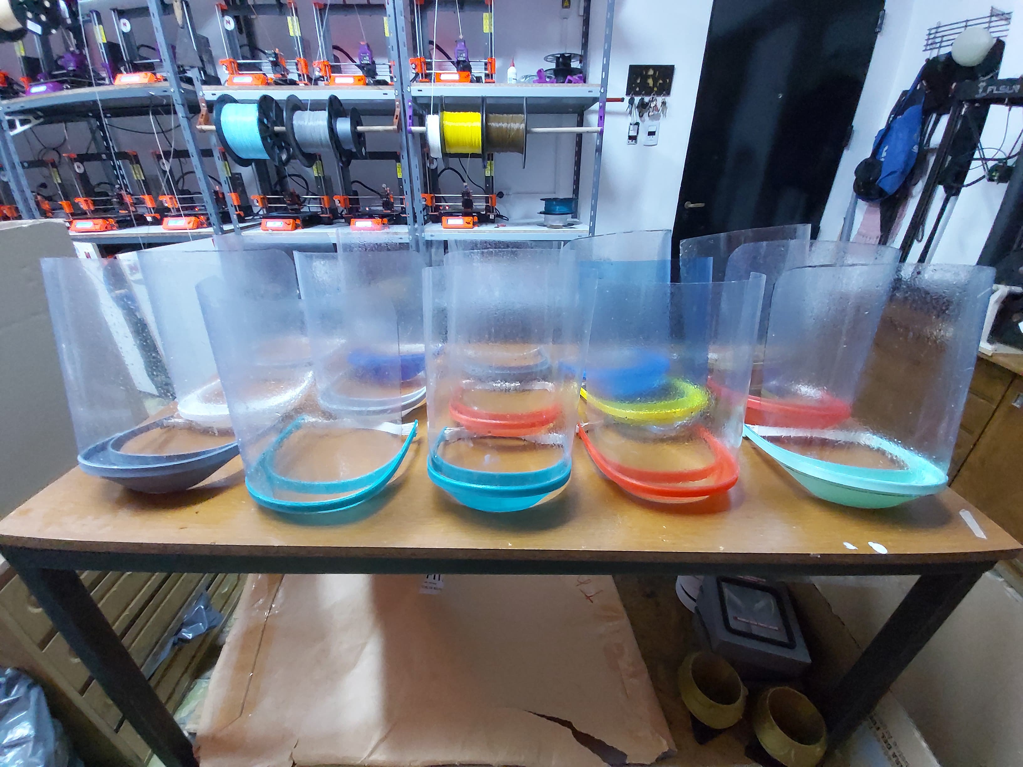 Losprotectores faciales para médicos y atrás uno de los equipos de impresión 3D.