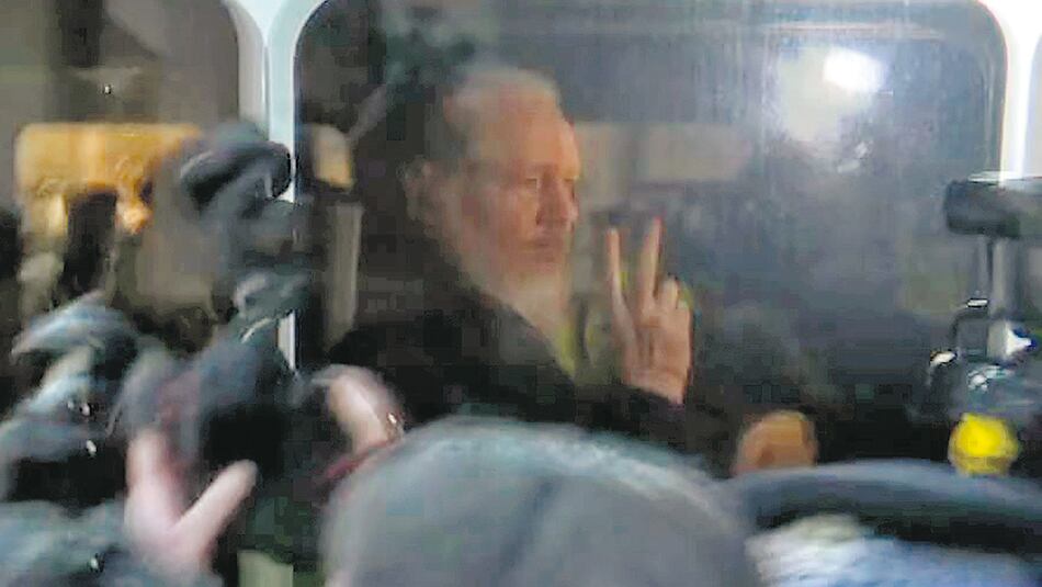 Assange saluda a sus seguidores camino al Departamento de Policía en Londres.